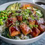 This healthy Baked Salmon Rice Bowl features tender salmon, creamy avocado, and edamame topped with a drizzle of spicy sriracha mayo.  