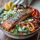 Bright Mediterranean Salmon Bowl features flaky salmon, creamy feta crumbles, fresh cilantro, and lemon wedges for a zesty, wholesome meal.