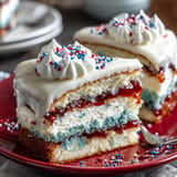 Moist Patriotic Poke Cake layers filled with vibrant gelatin, topped with creamy ganache.