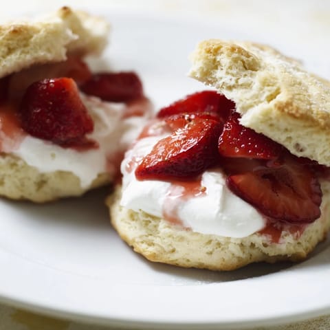 Fluffy strawberry shortcake biscuits are piled high with ripe berries and rich whipped cream.