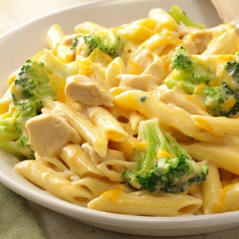 Family-style Chicken Broccoli Cheddar Pasta served warm, topped with extra sharp cheddar and fresh herbs.