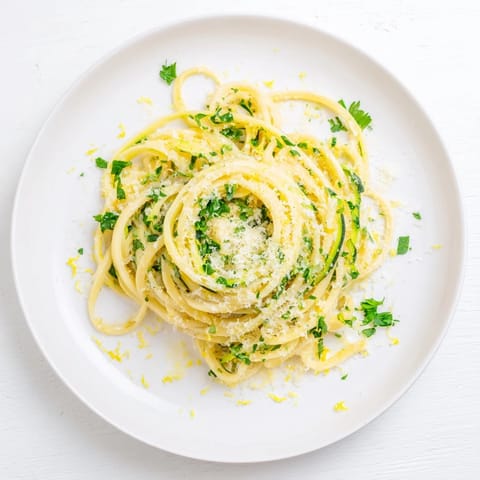 Golden Lemon Zucchini Pasta served in a white bowl with a glass of white wine, perfect for weeknight dinners.