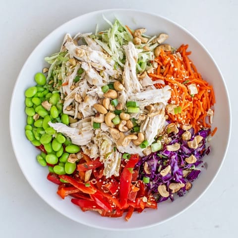 Close-up of Edamame Crunch Chicken Salad, featuring shredded chicken, crisp cabbage, carrots, and edamame tossed in zesty ginger dressing.