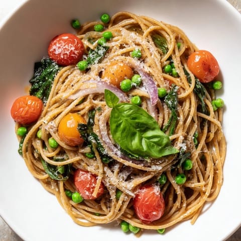 Steaming Spring Veggie One-Pot Spaghetti with fresh peas, spinach, and halved cherry tomatoes.  