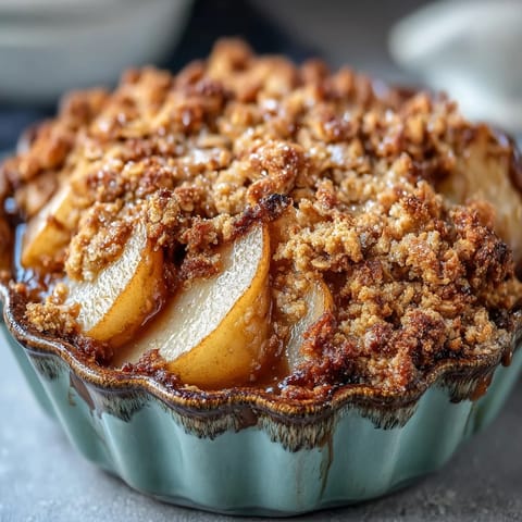 Freshly baked Pear Crumble in a rustic baking dish, showcasing juicy pear slices beneath a thick, buttery crumble topping ready for dessert.