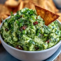 Creamy edamame guacamole with ripe avocado and fresh cilantro served with crispy baked pita chips.  