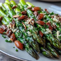 Fresh asparagus spears glisten with lemon butter sauce and crunchy toasted almonds in a vibrant spring side dish.  